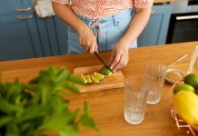 close up of woman cutting lime with knife and making mocktail at home kitchen